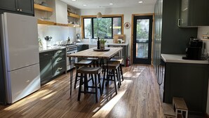 A modern kitchen with a central island, wooden flooring, and built-in appliances.