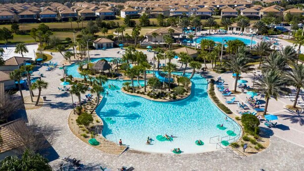 Et resort med en central swimmingpool, omgivet af palmer og opholdsområder.