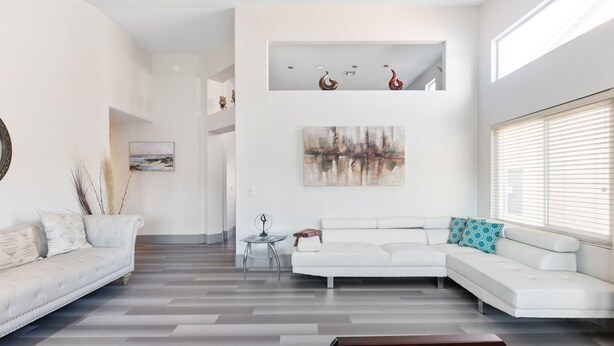 A modern living room with a white sofa, a coffee table, and a painting on the wall.