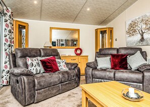A living room with two leather sofas, a wooden coffee table, and a mirror above a wooden cabinet.