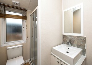 A bathroom with a toilet, a shower, a sink, and a mirror. - 3 bedroom accommodation in Carnforth (Carnforth)
