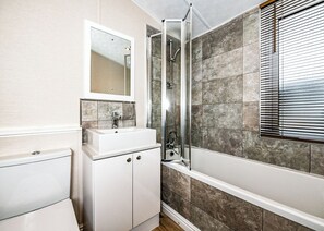 A bathroom with a shower, a sink, a mirror, and a toilet.