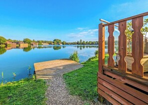 Una terraza de madera con vistas despejadas a un lago tranquilo y edificios lejanos.
