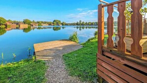 A wooden deck with a clear view of a calm lake and distant buildings.
