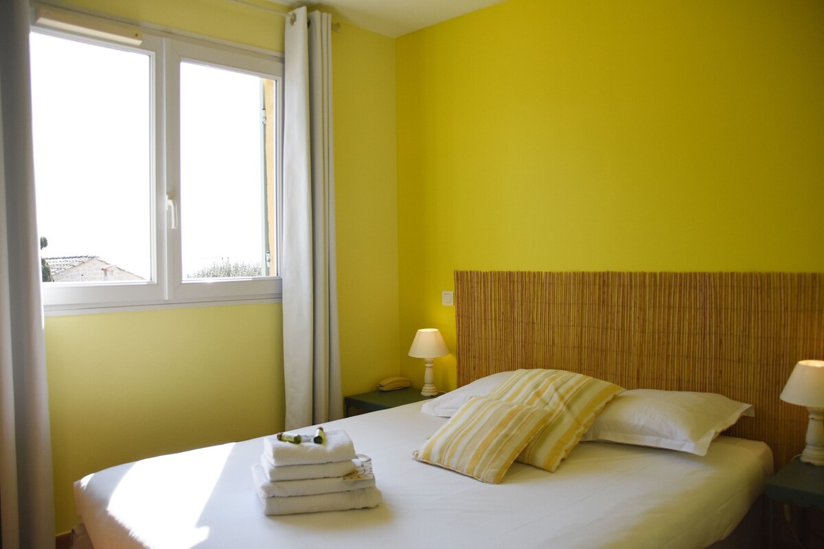 A hotel room with a bed, a window, and a nightstand with a lamp.