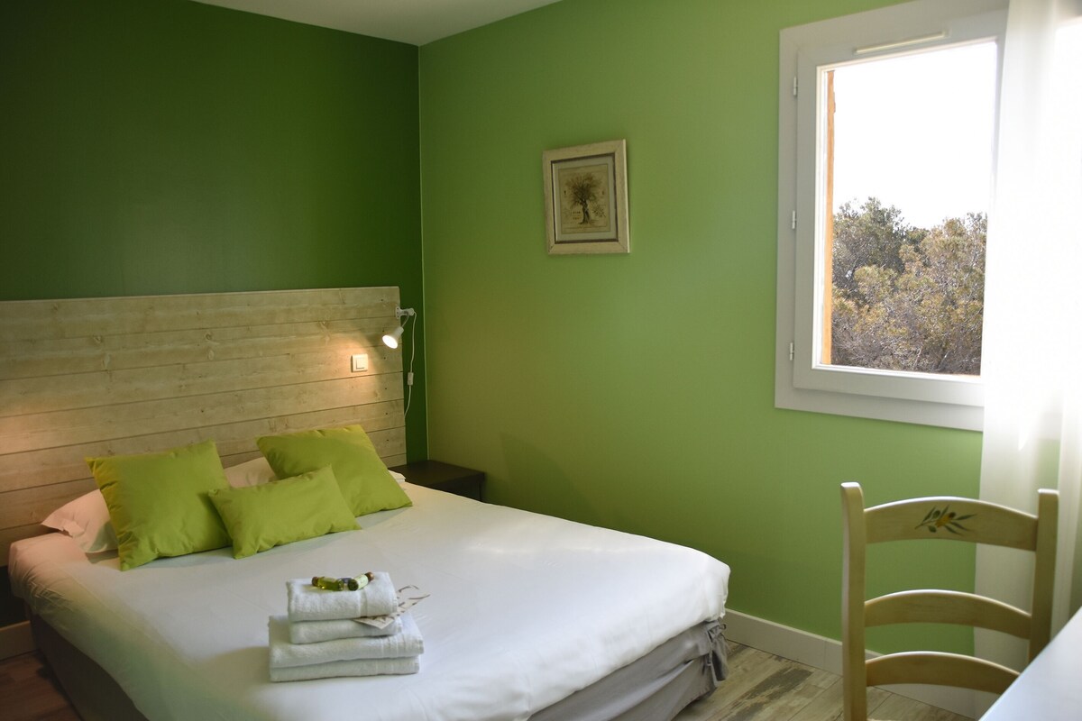 A room with a bed, green walls, a wooden headboard, a framed picture, and a window.