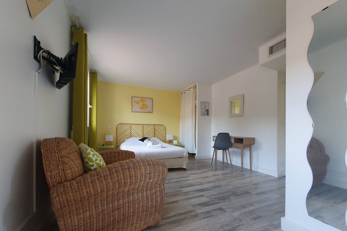 Ein Schlafzimmer mit Bett, Stuhl, Schreibtisch und einem Rattansofa.