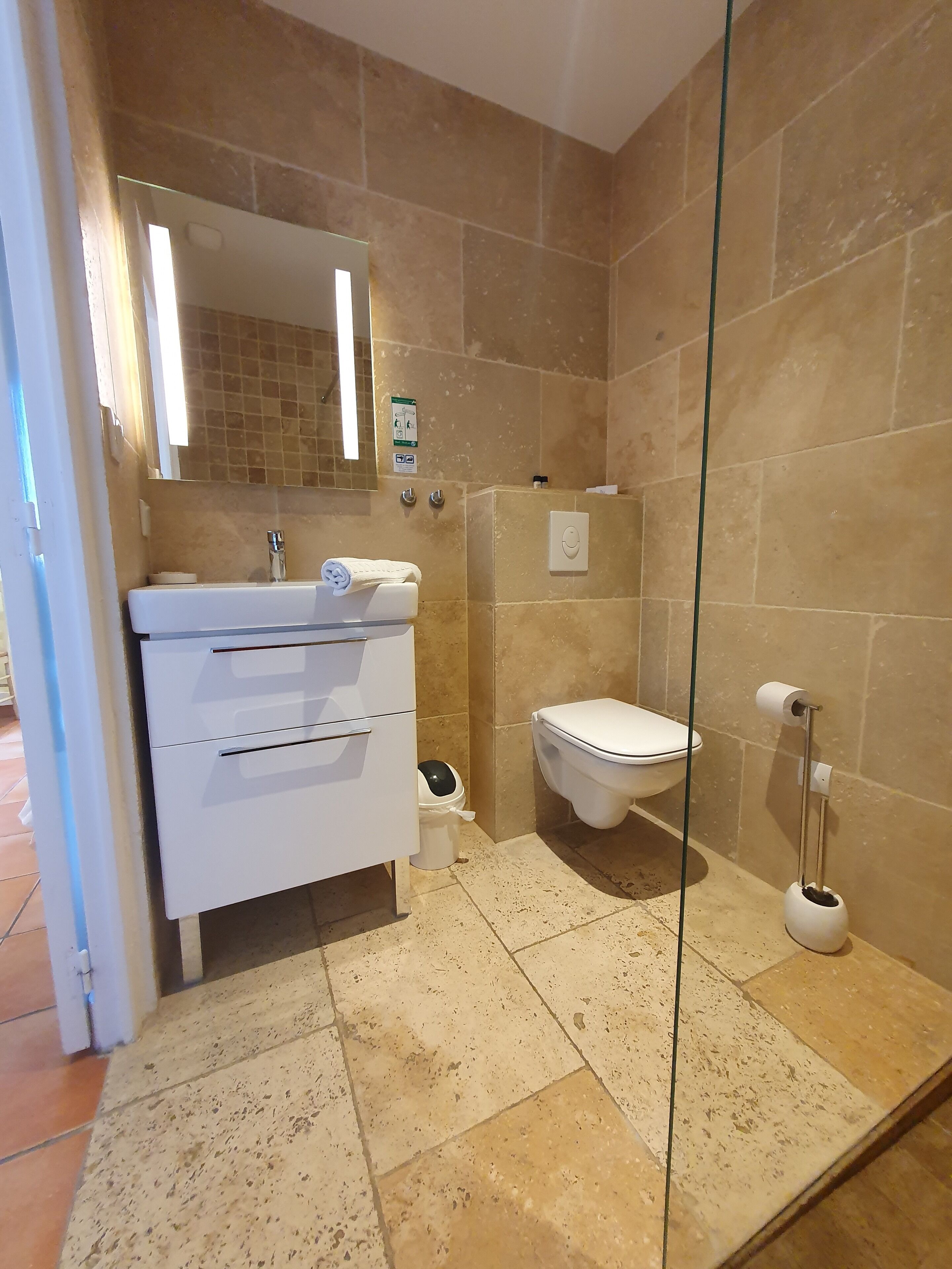 A bathroom with a white vanity, a toilet, and a glass shower enclosure.