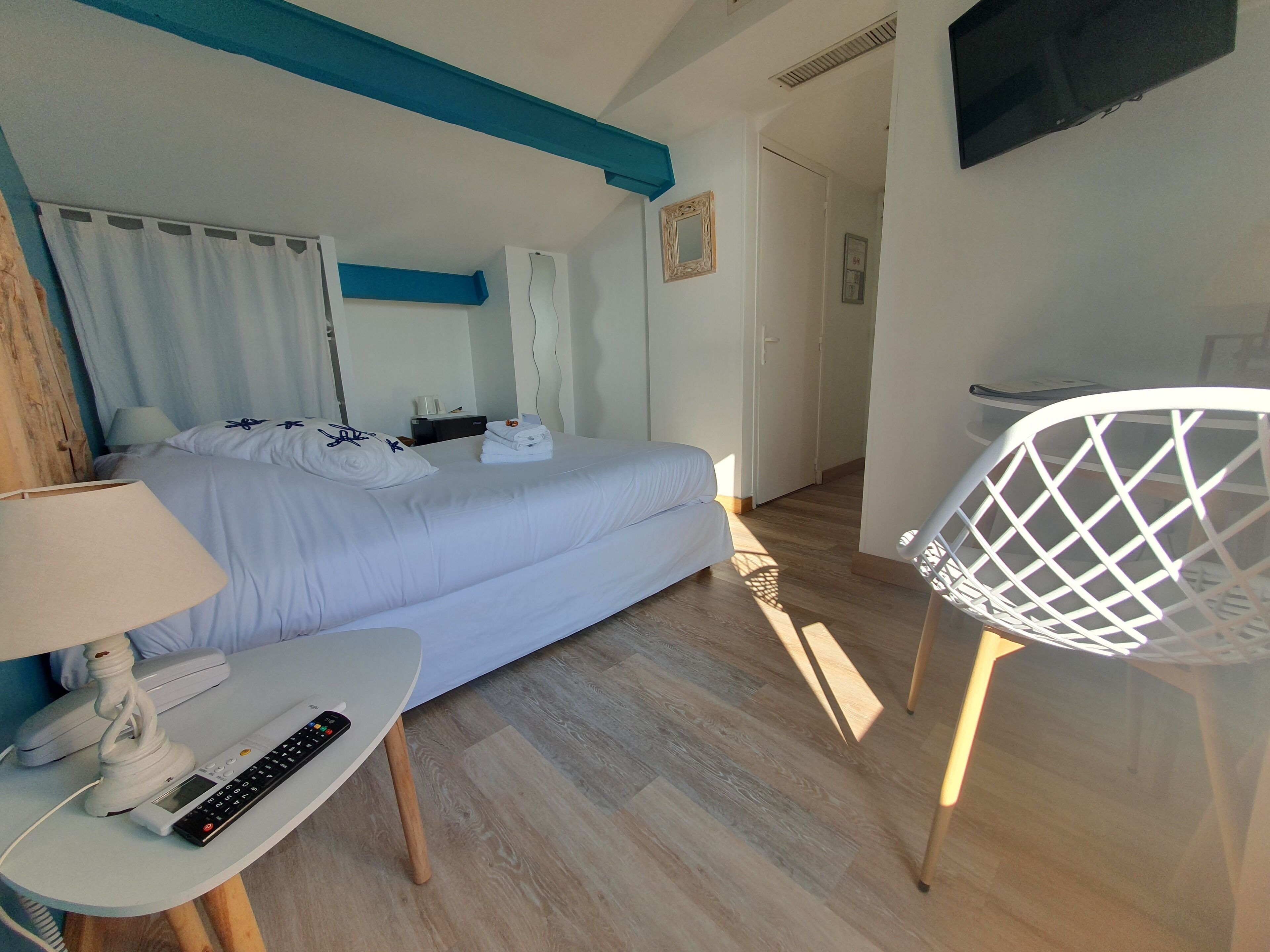A hotel room with a bed, a desk with a lamp, a chair, and a TV.