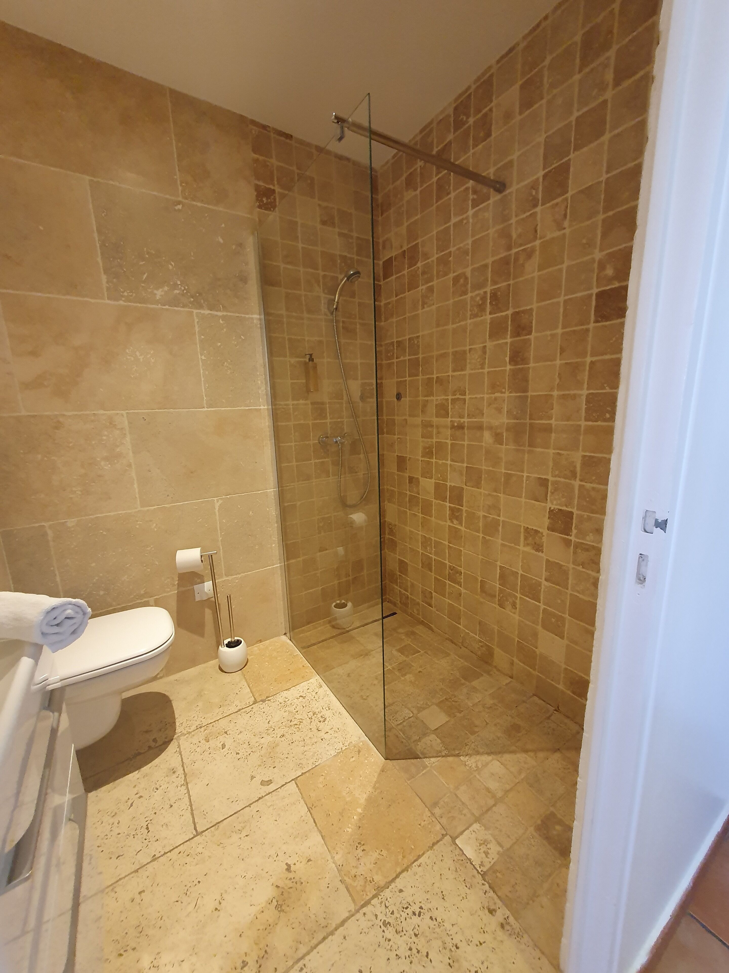 A bathroom with a glass-enclosed shower, a toilet, and a sink.