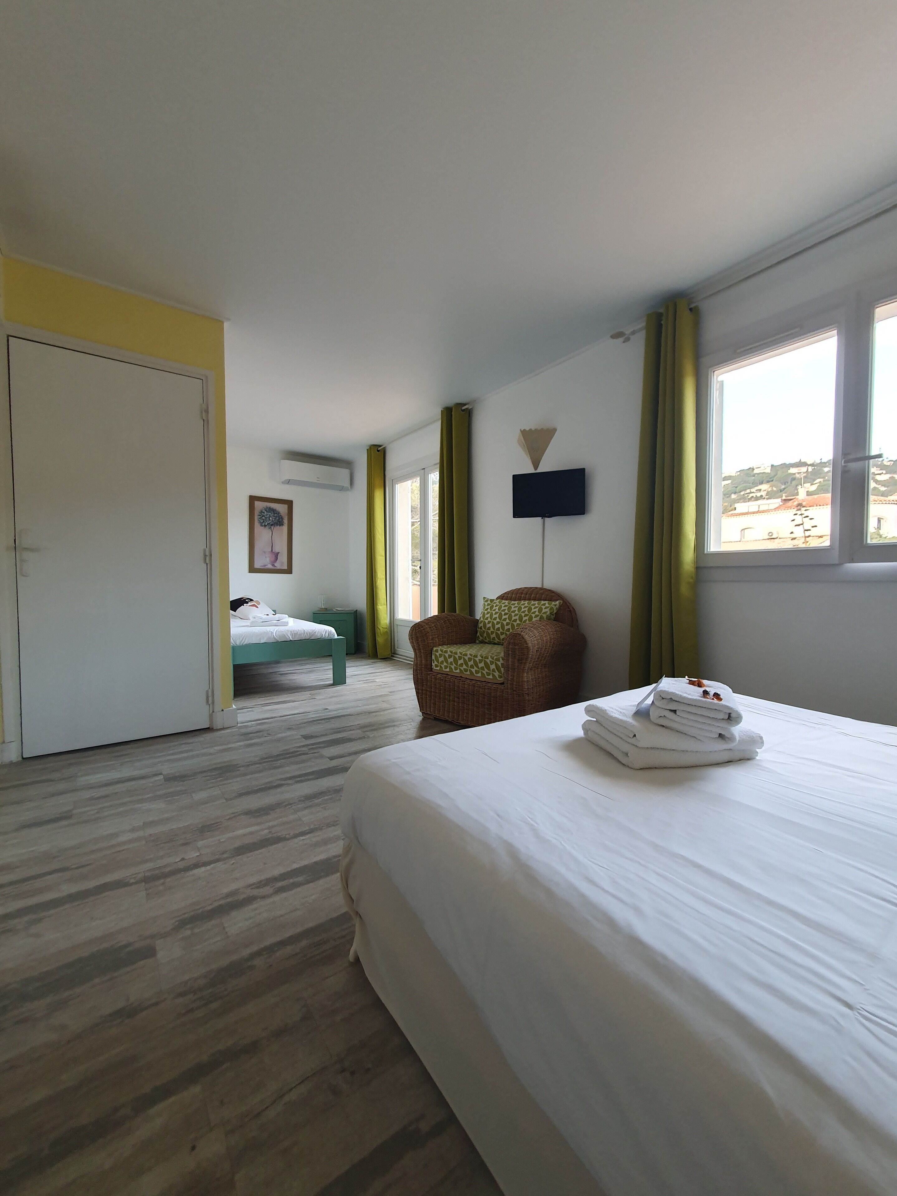 Une chambre d’hôtel avec un lit, une chaise, un bureau, une fenêtre et une porte.