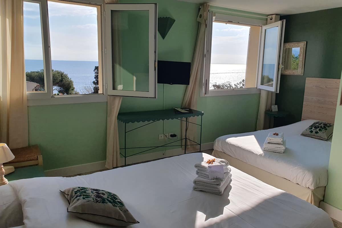 Ein Zimmer mit zwei Betten, einem Schreibtisch und Meerblick.