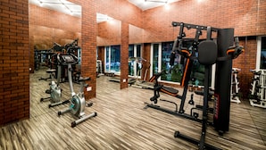 Een sportschool met bakstenen muren, spiegelende plafonds en diverse fitnessapparaten.