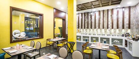 A restaurant with yellow walls, multiple dining tables, and chairs.