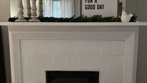A fireplace with a mantel decorated with a sign, a potted plant, and a small table. - Mt. Adams - Rare Gem! Minutes to Downtown (Cincinnati)