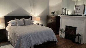 A bedroom with a large bed, a nightstand, a dresser, a fireplace, and a wall with a motivational quote. - Mt. Adams - Rare Gem! Minutes to Downtown (Cincinnati)