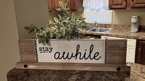 A kitchen with wooden cabinets, a granite countertop, and a sign that reads "stay awhile". - Mt. Adams - Rare Gem! Minutes to Downtown (Cincinnati)