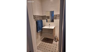 A bathroom with a white sink, a mirror, and a patterned floor.