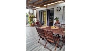 A wooden dining table with chairs, a clock on the wall, and potted plants.