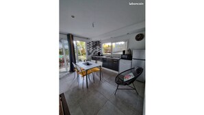 A modern kitchen with a dining area, large windows, and a view of the outdoors.