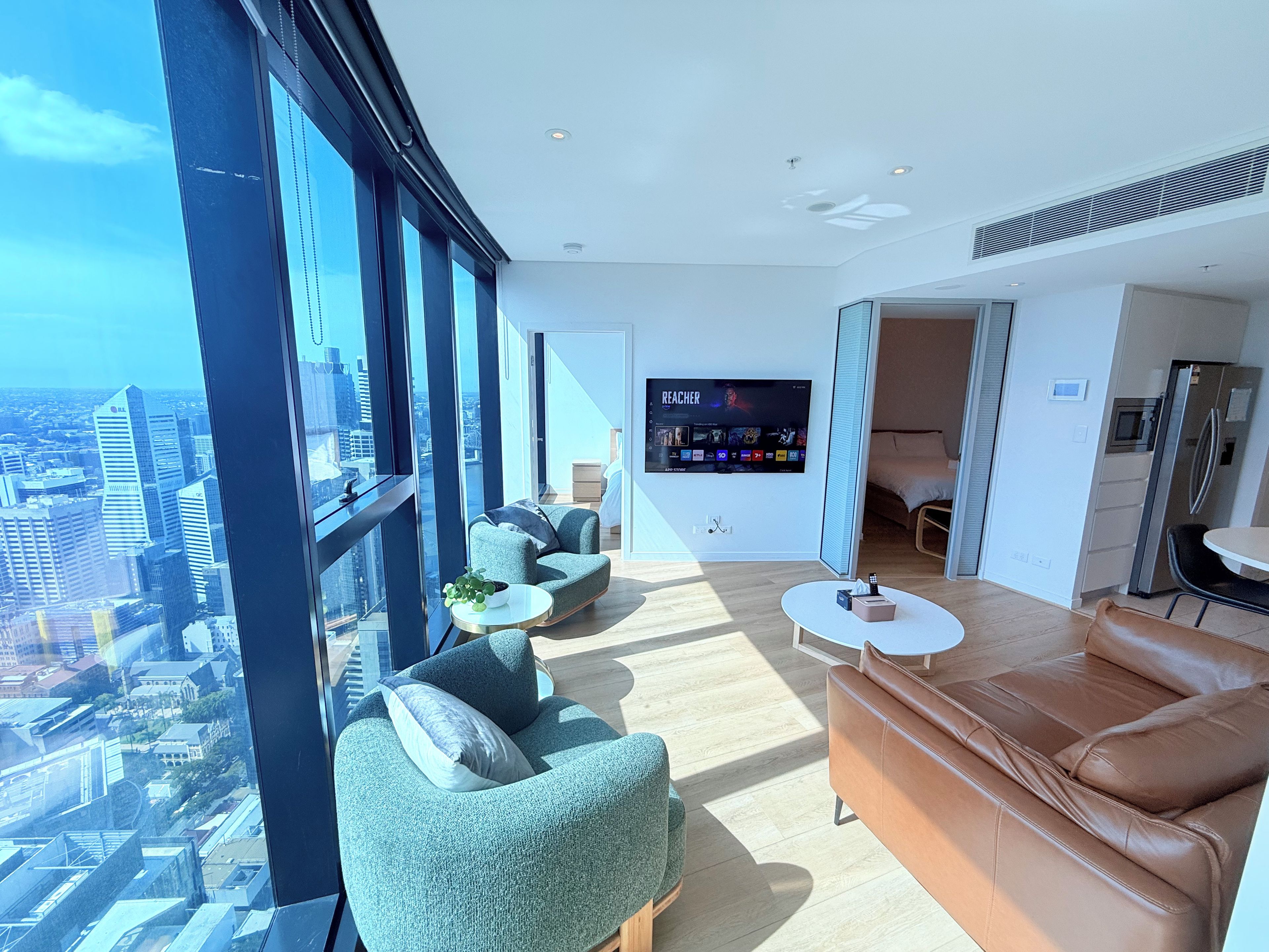 A modern living room with a large TV, comfortable seating, and a city view.