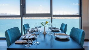 Een eettafel voor vier personen, met uitzicht op een waterpartij en een verre brug.