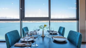 A dining table set for four with a view of a body of water and a distant bridge.