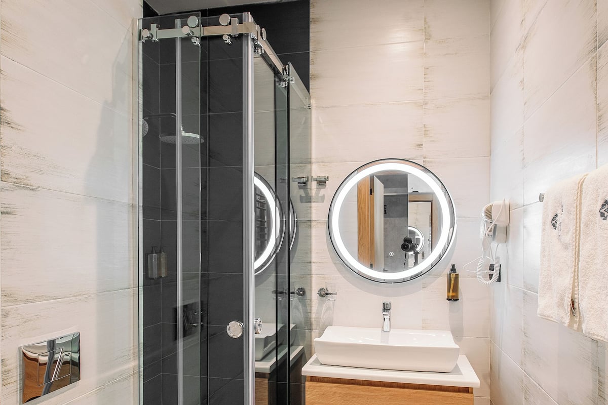 Une salle de bain moderne avec une douche à parois de verre, un lavabo avec un miroir et des toilettes.