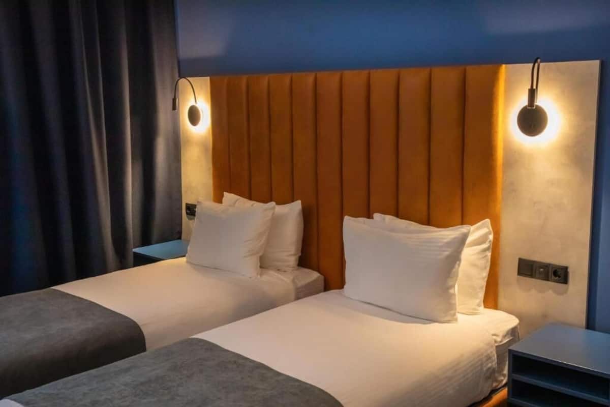 Une chambre d’hôtel avec deux lits, une tête de lit en bois et des lampes de chevet.