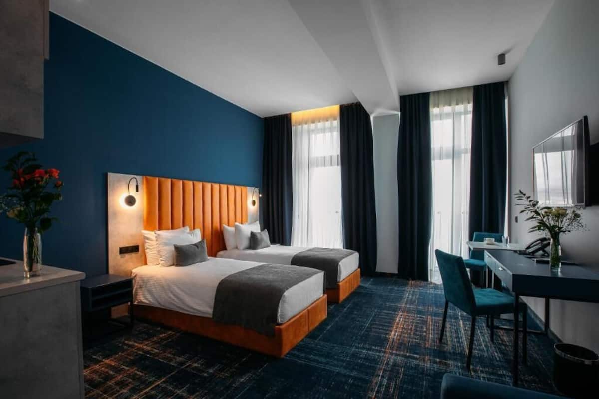 Une chambre d’hôtel avec deux lits, un bureau, une chaise et un téléviseur.