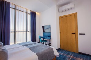 Een hotelkamer met een bed, bureau, stoel en een houten deur.