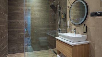 A modern bathroom with a glass-enclosed shower, a white sink, and a wooden vanity.