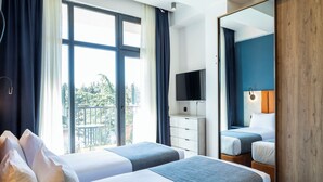 A hotel room with two beds, a TV, a dresser, and a balcony with outdoor furniture. - Gino Seaside Tbilisi, Trademark Collection by Wyndham (Tbilisi)