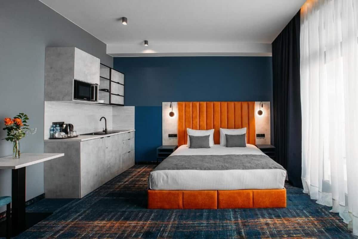 Une chambre d’hôtel moderne dotée d’un grand lit, d’une kitchenette et d’une salle de bain.