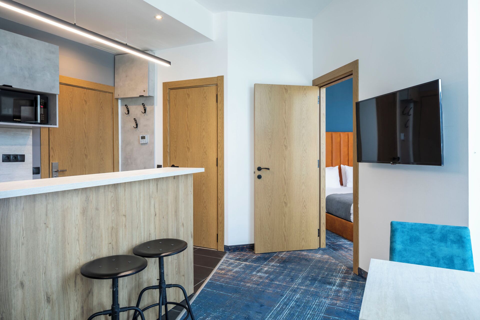 Una habitación de hotel compacta con kitchenette, una cama y televisión.