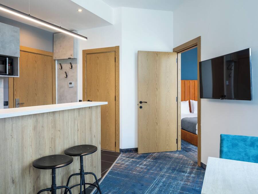 Una habitación de hotel compacta con kitchenette, una cama y televisión.