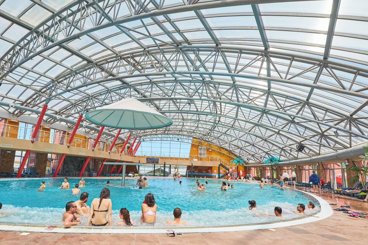 Une piscine intérieure dotée d’un toit en verre et de plusieurs niveaux.
