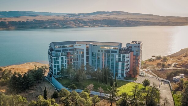 Ein modernes Hotel mit einem zentralen Innenhof, umgeben von Hügeln und einem See.