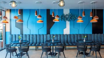 Ein modernes Interieur mit blauem Wanddesign, einer Sitzecke und mehreren Tischen und Stühlen.