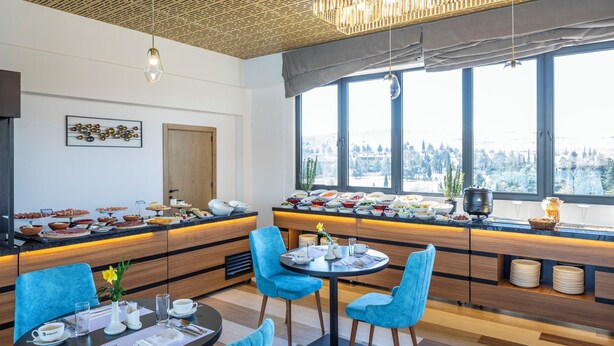 A modern dining area with a buffet, blue chairs, and a view of a snowy landscape through large windows. - Gino Seaside Tbilisi, Trademark Collection by Wyndham (Tbilisi)
