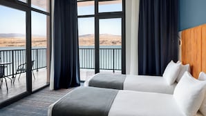 Une chambre d’hôtel avec deux lits, un balcon et une vue sur un paysage désertique.