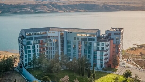 Un hôtel moderne à plusieurs étages, doté de grandes fenêtres et offrant une vue sur un lac.