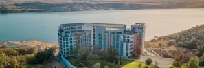 A modern hotel with multiple floors, large windows, and a view of a lake. - Gino Seaside Tbilisi, Trademark Collection by Wyndham (Tbilisi)