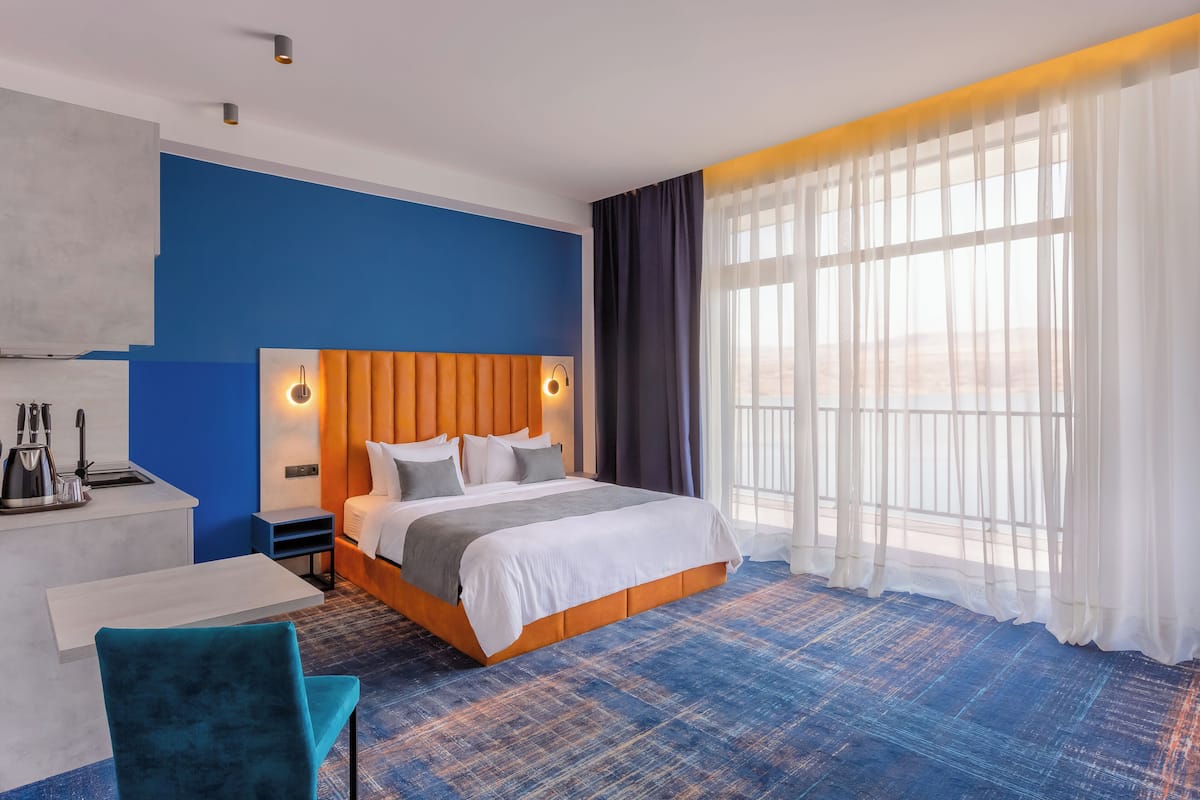 Une chambre d’hôtel avec un lit, un bureau, une chaise et une grande fenêtre avec des rideaux.