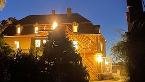 A two-story house with a staircase leading to the upper floor, surrounded by trees.