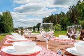 A wooden table set for a meal with white bowls and wine glasses, surrounded by a natural landscape. - Villa Sophienschlösschen near Berlin - 5 lakes, 3500sqm garden + FREE sauna (Marienwerder)