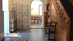 A hallway with a checkered floor, wooden walls, a staircase, and a seating area with chairs.