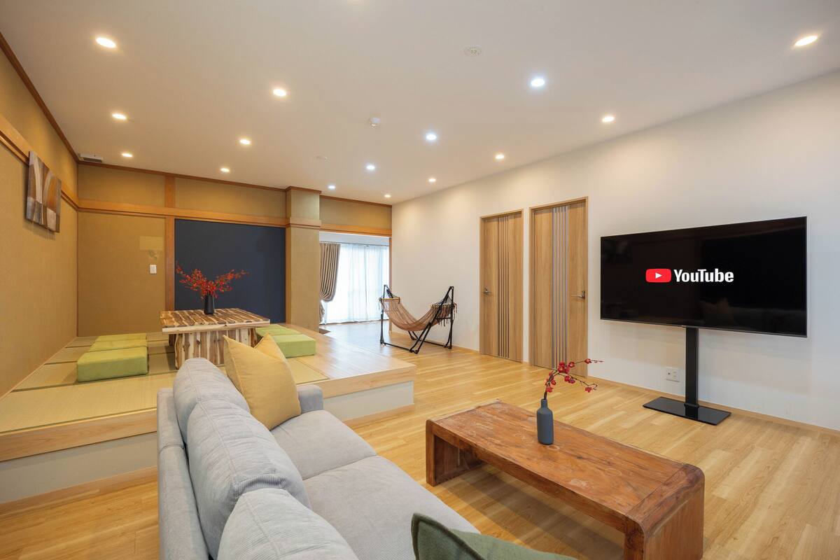 A modern living room with a sofa, coffee table, and a flat-screen TV mounted on the wall.