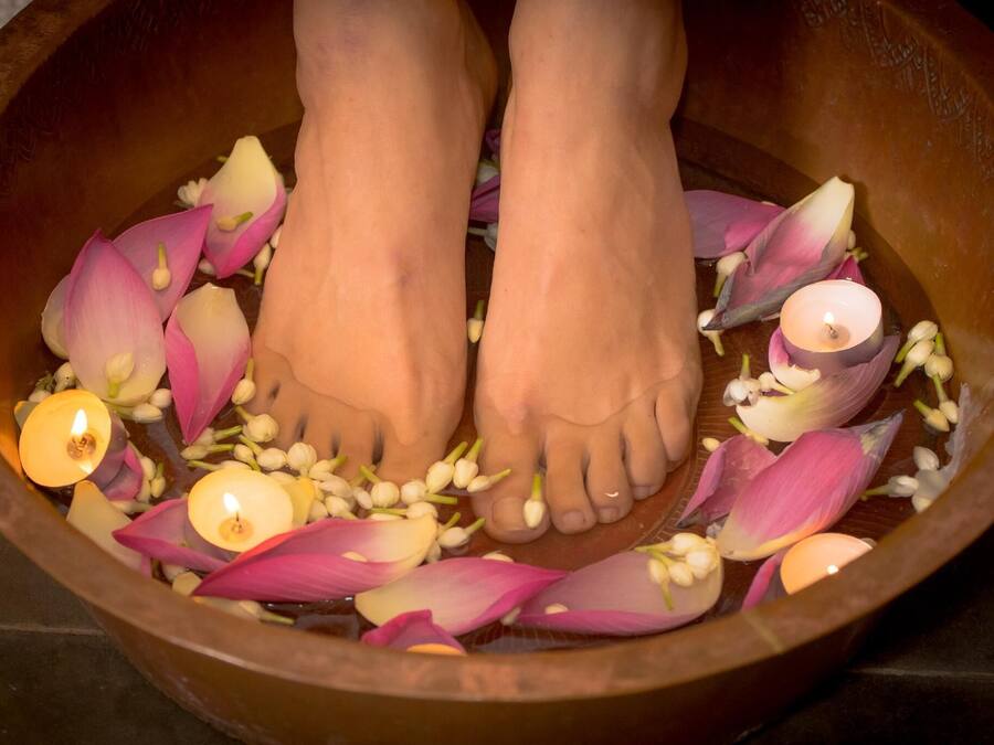 A wooden bowl with water, lotus leaves, and candles.