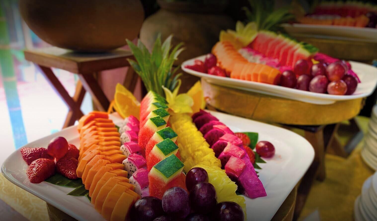 A variety of sliced fruits arranged on plates, including watermelon, pineapple, and dragon fruit.